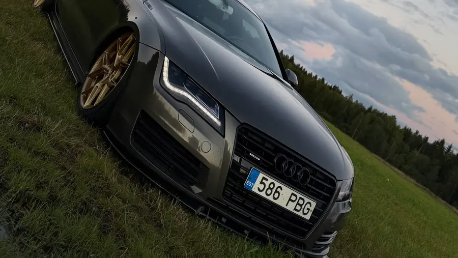 Tummanharmaa Audi A7 pronssisilla vanteilla nurmikolla