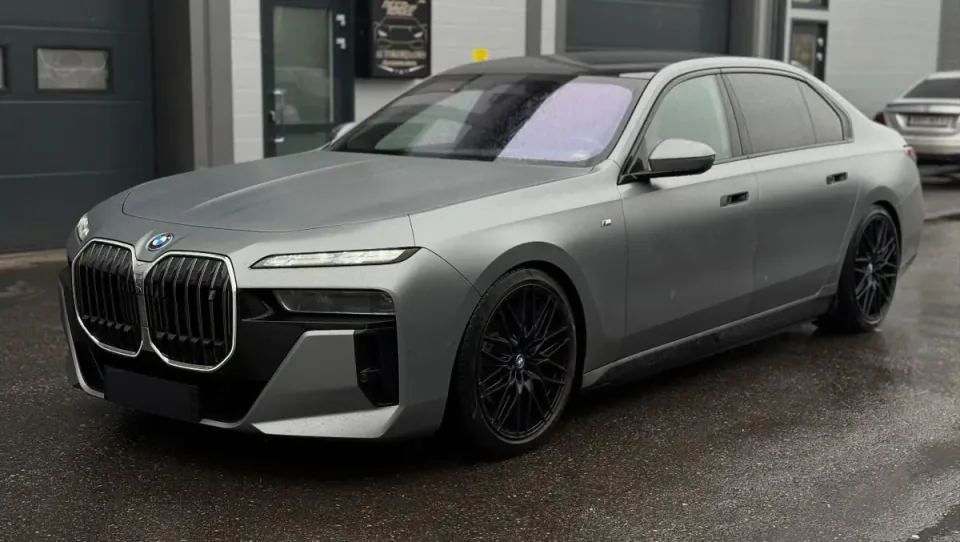 Harmaa BMW i7 mustilla vanteilla hallin pihalla